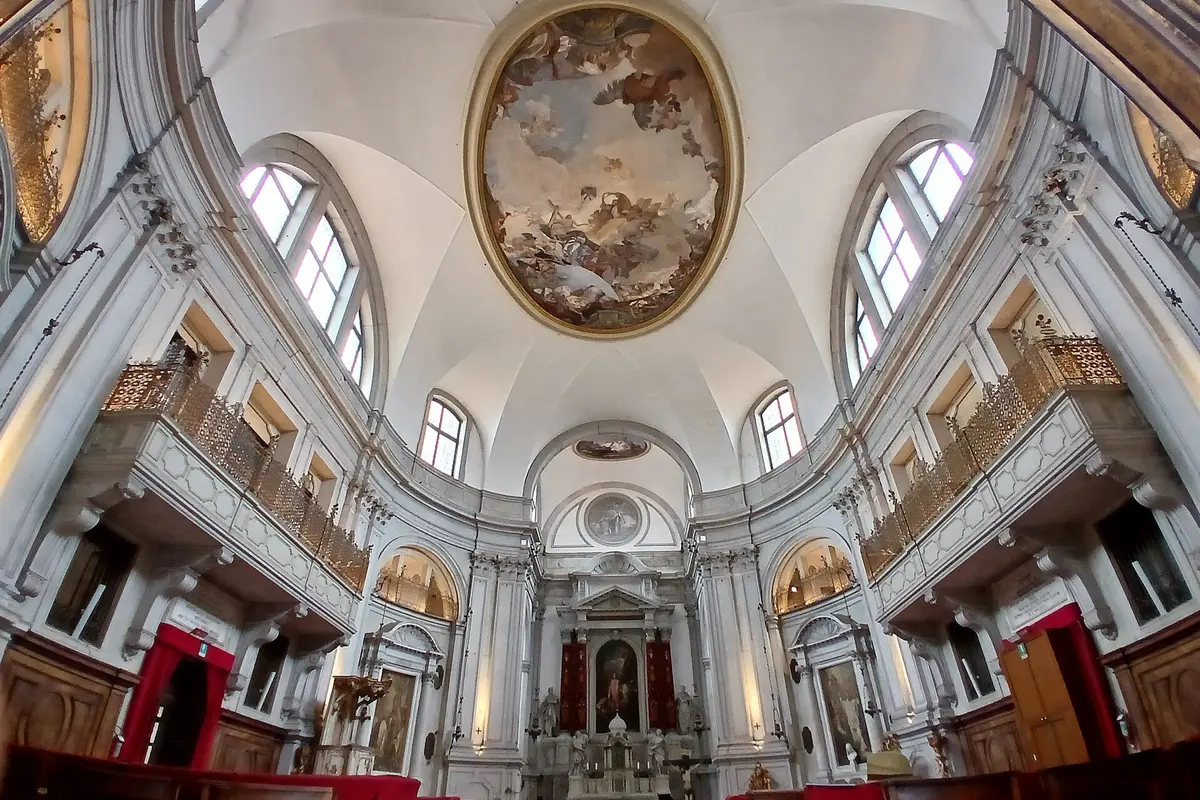 The oval white interior of the Church of the Pietà, with a Tiepolo fresco on the ceiling and grilled galleries along both side walls